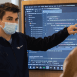 Man pointing at screen with code on 