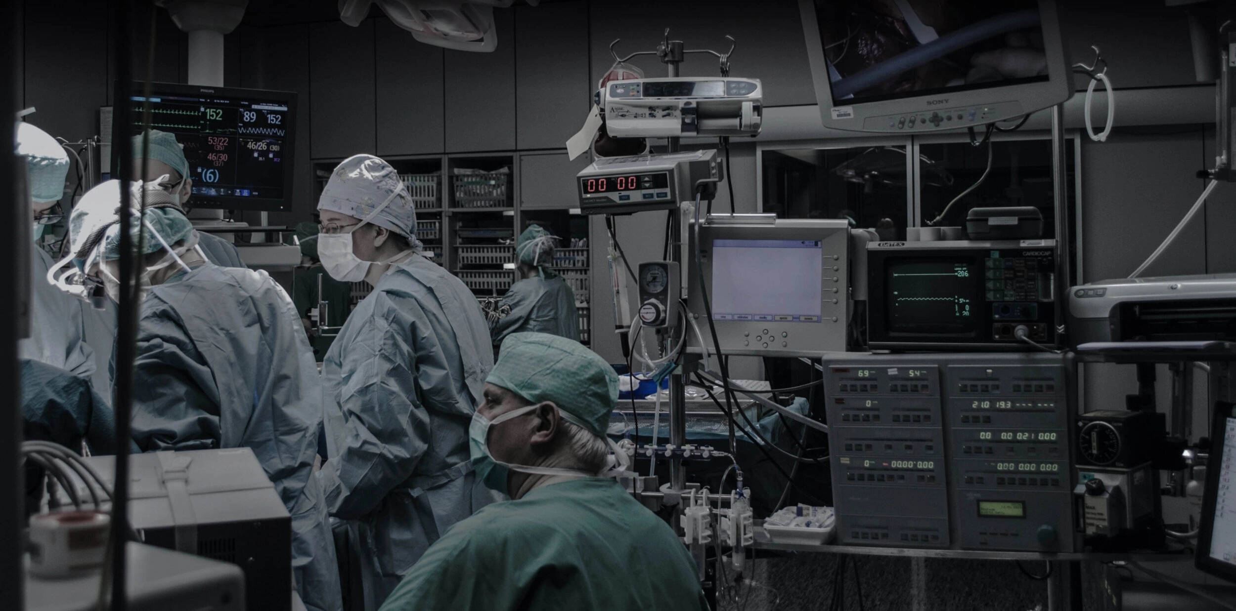 People wearing masks and gowns in an operating theatre environment