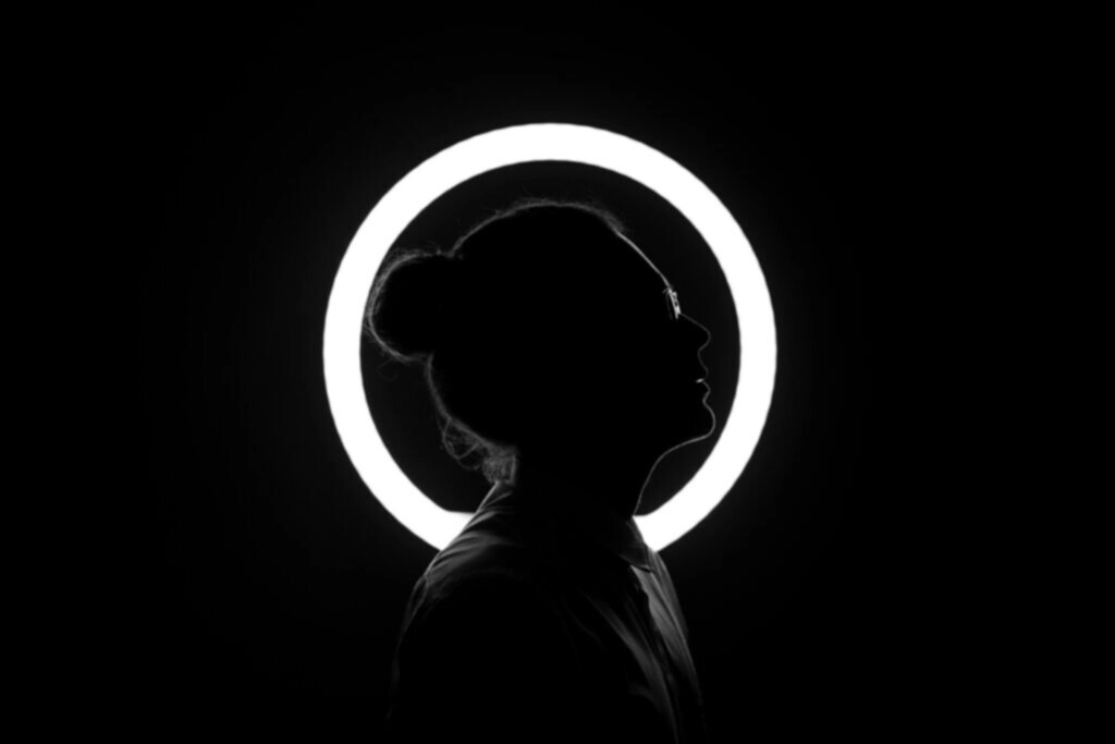 Mujer con moño y gafas perfil lateral retroiluminado con luz blanca anular