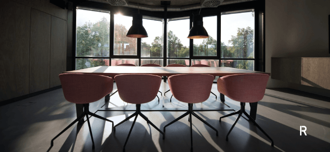 Desk with 8 pink chairs in room with big windows