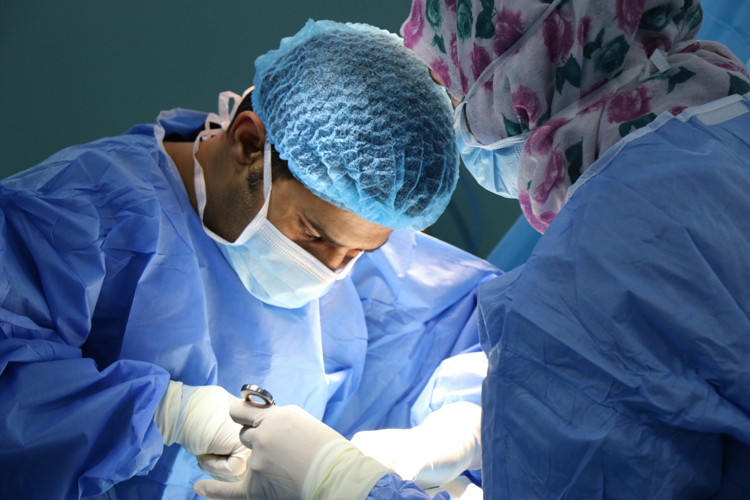 Doctor conducting surgery with another healthcare staff holding forceps