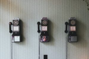 Three old fashioned wall phones hanging on a wallpapered wall