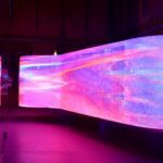 Purple, pink and blue LED design exhibit in darkened room.