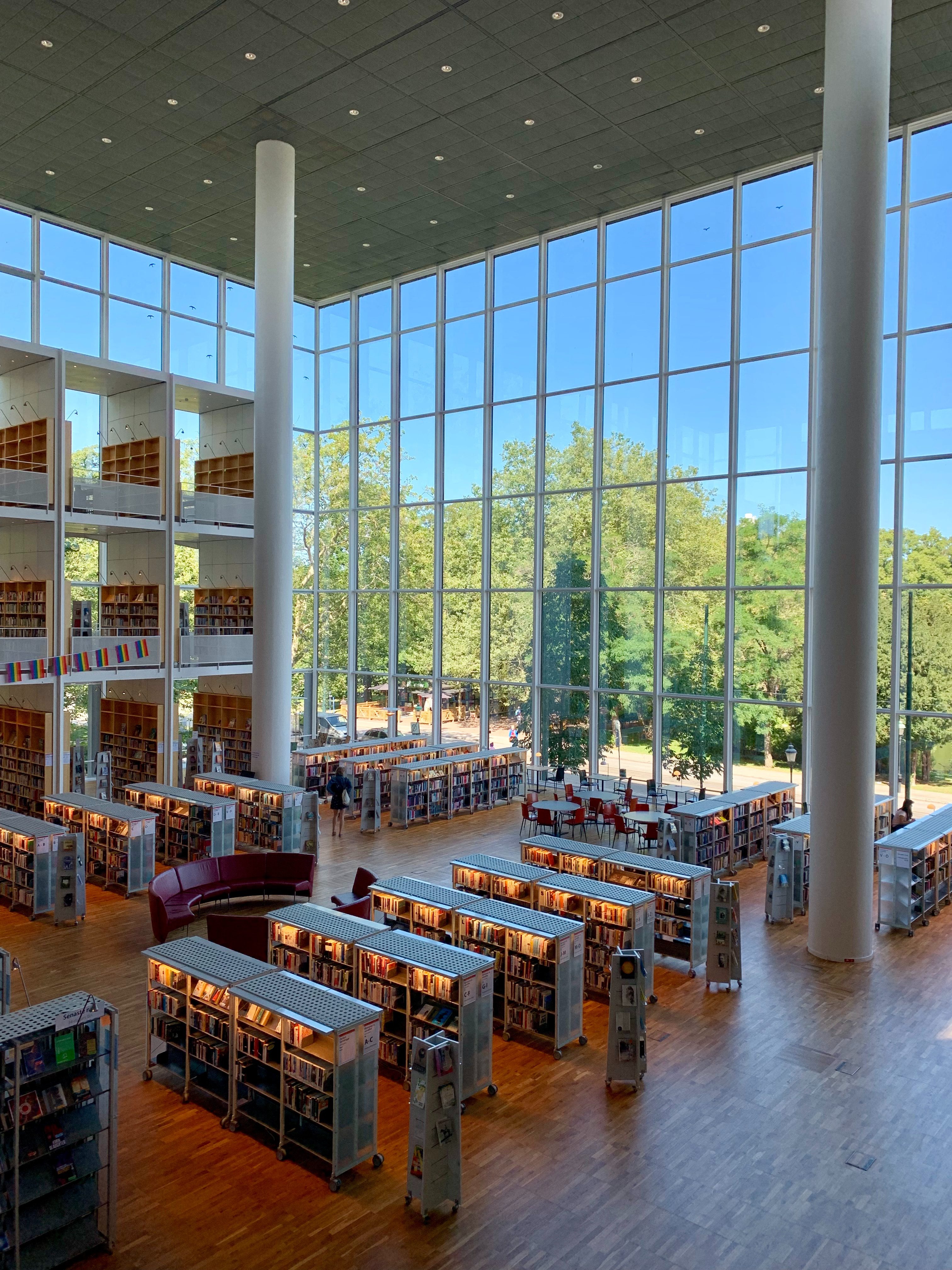 Library with big windows and green trees outside, shelves with books on inside
